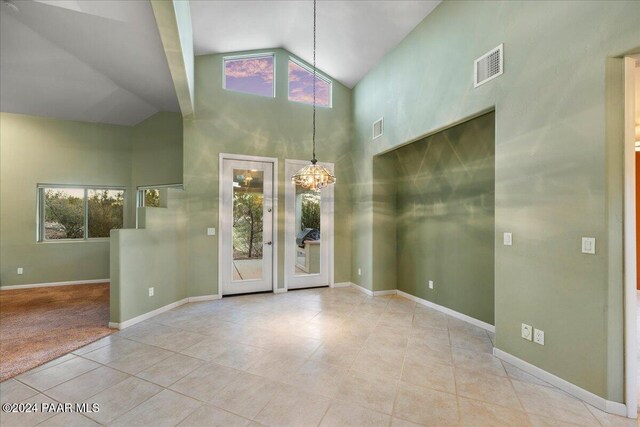 entrance foyer with light tile patterned flooring, high vaulted ceiling, and an inviting chandelier