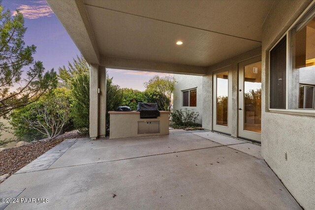 patio terrace at dusk with a grill and an outdoor kitchen