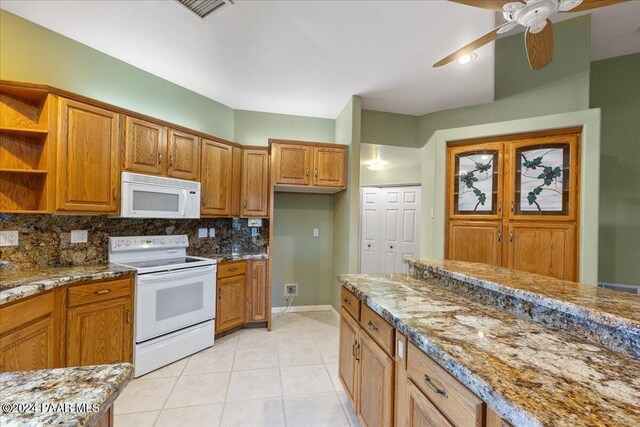 kitchen featuring light stone countertops, white appliances, light tile patterned floors, and tasteful backsplash