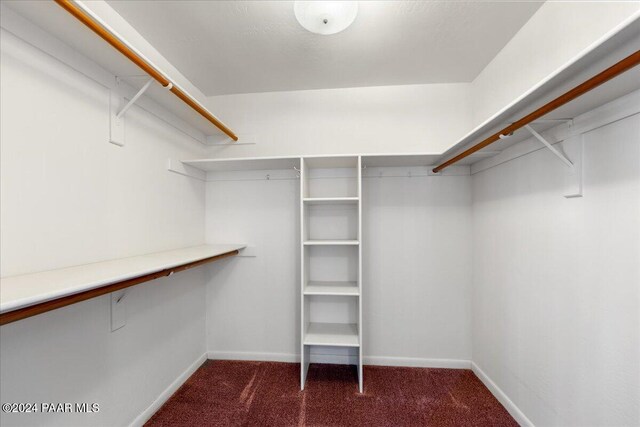 spacious closet featuring dark colored carpet