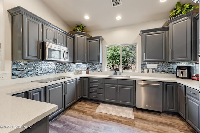 kitchen featuring gray cabinetry, dark hardwood / wood-style floors, backsplash, and stainless steel appliances