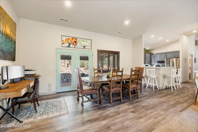 dining space with hardwood / wood-style flooring, french doors, and vaulted ceiling