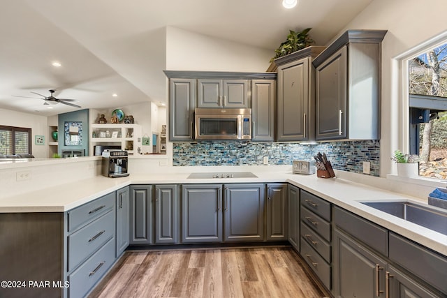 kitchen featuring gray cabinetry, ceiling fan, tasteful backsplash, wood-type flooring, and vaulted ceiling