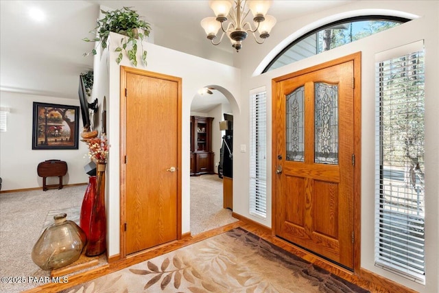 carpeted foyer featuring an inviting chandelier