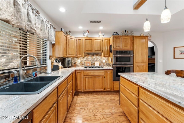 kitchen featuring sink, appliances with stainless steel finishes, tasteful backsplash, and light stone counters