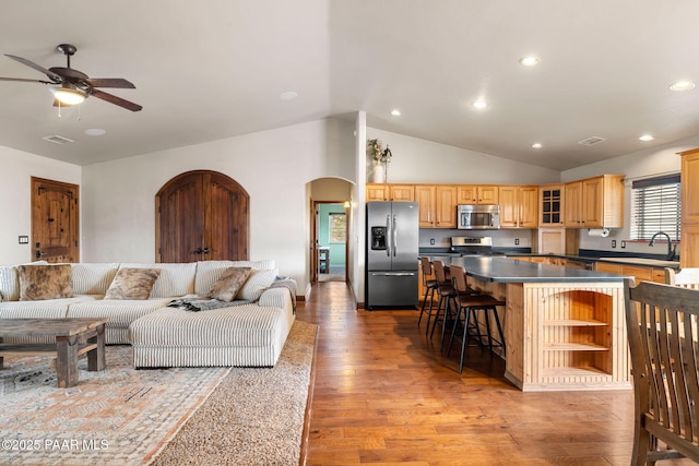 living room with visible vents, a ceiling fan, arched walkways, light wood-style floors, and vaulted ceiling