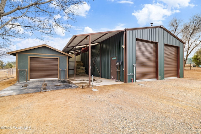 exterior space featuring an outbuilding, a garage, an outdoor structure, and dirt driveway