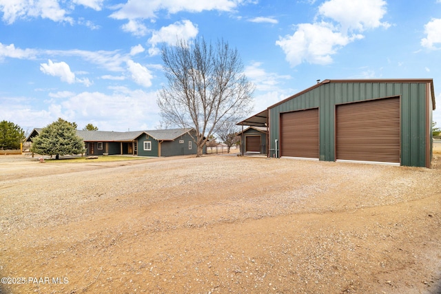 view of front of house featuring an outdoor structure, a detached garage, and driveway