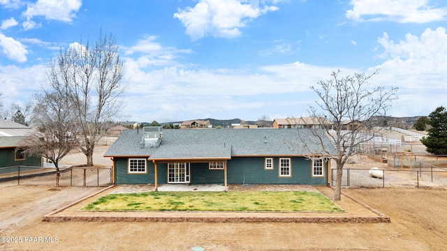 ranch-style home with a gate, fence, roof with shingles, a front lawn, and a patio area