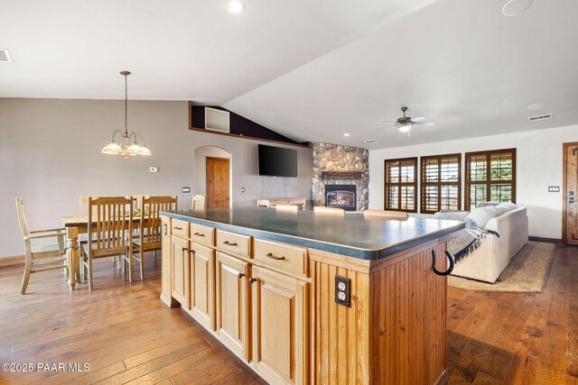 kitchen with dark countertops, a kitchen island, visible vents, and ceiling fan