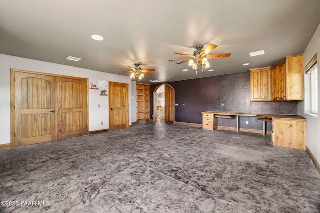 unfurnished living room featuring arched walkways, visible vents, baseboards, and a ceiling fan