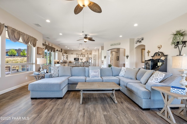 living room featuring arched walkways, recessed lighting, visible vents, dark wood-type flooring, and baseboards