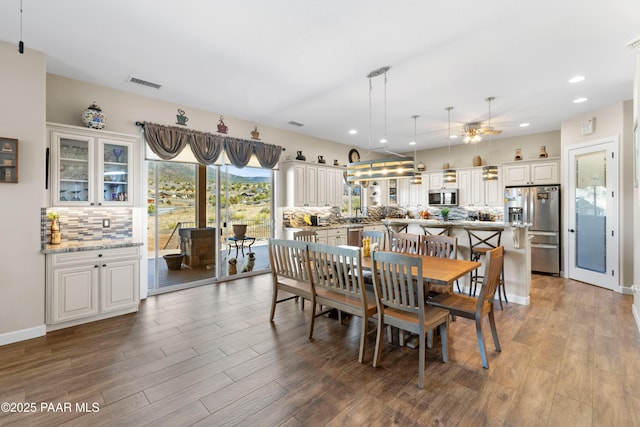 dining room with baseboards, wood finished floors, visible vents, and recessed lighting