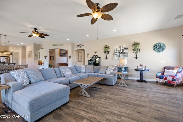 living area with dark wood-style floors, baseboards, arched walkways, and recessed lighting