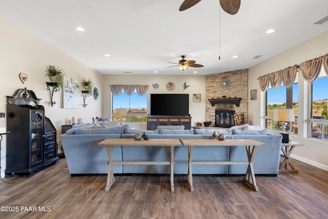 living area with recessed lighting, visible vents, a stone fireplace, and wood finished floors