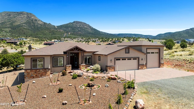 ranch-style house with stone siding, a mountain view, an attached garage, and stucco siding