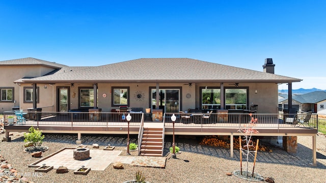 rear view of house featuring an outdoor fire pit, a ceiling fan, a wooden deck, a chimney, and a patio area