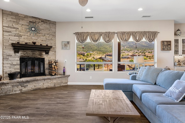 living room with a stone fireplace, recessed lighting, wood finished floors, visible vents, and baseboards