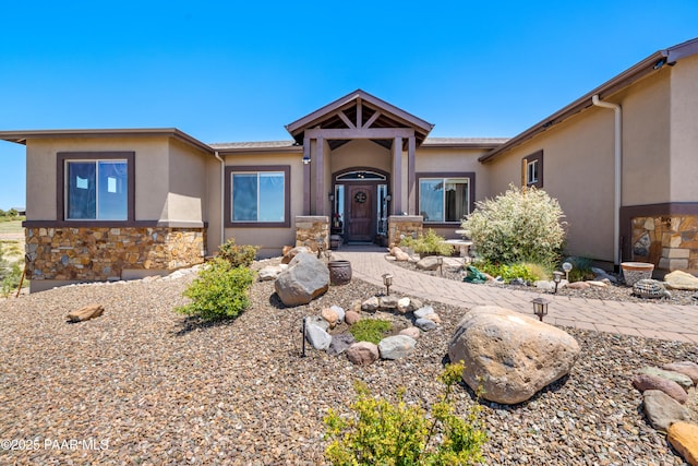 view of front of property featuring stone siding and stucco siding