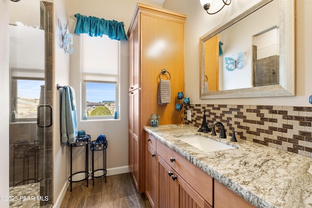 full bathroom with a stall shower, wood finished floors, vanity, and decorative backsplash