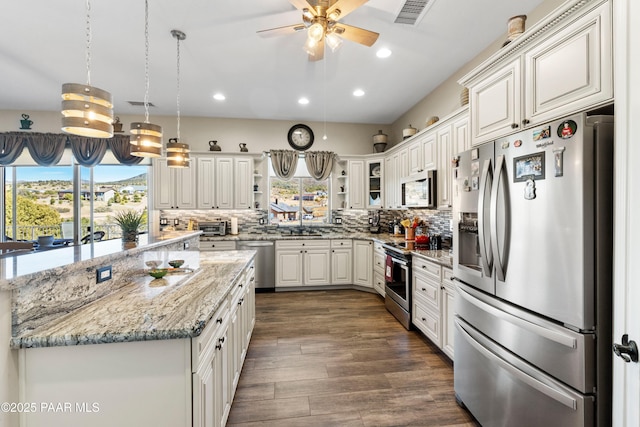 kitchen featuring stainless steel appliances, visible vents, decorative backsplash, and dark wood-style floors