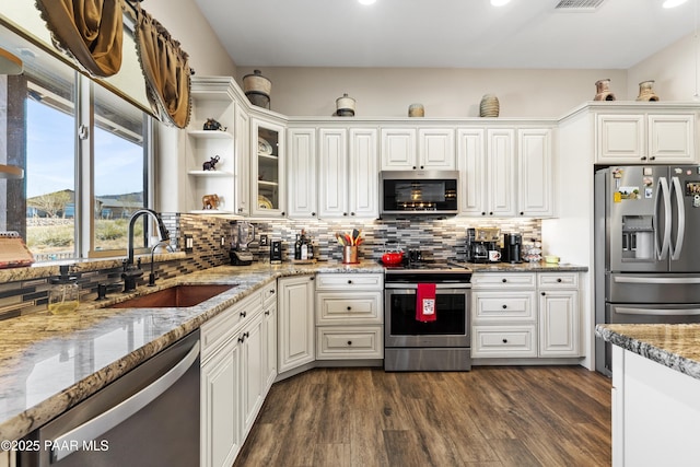 kitchen featuring appliances with stainless steel finishes, dark wood-style flooring, a sink, and backsplash