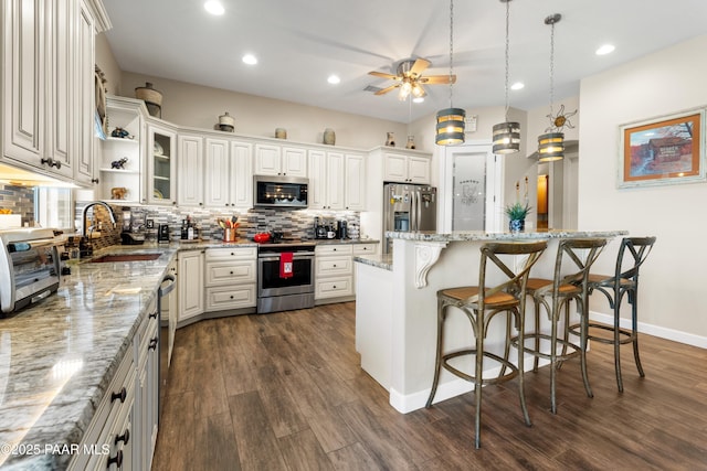 kitchen featuring a kitchen bar, appliances with stainless steel finishes, backsplash, and a sink