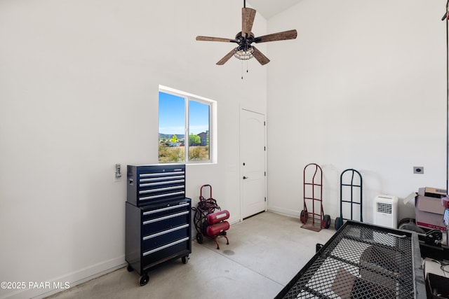 exercise area with a ceiling fan, a high ceiling, and baseboards