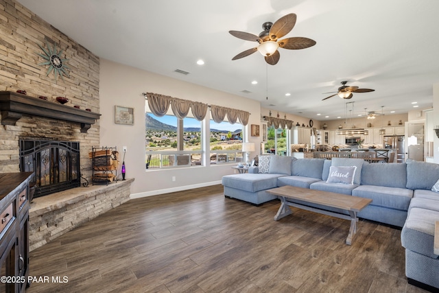 living area featuring baseboards, visible vents, dark wood-type flooring, a fireplace, and recessed lighting