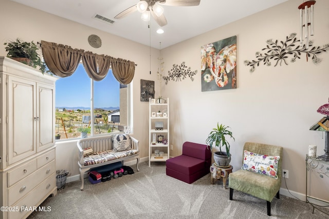 living area featuring carpet floors, visible vents, baseboards, and a ceiling fan