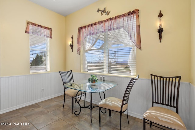 dining space featuring tile patterned flooring and a wainscoted wall