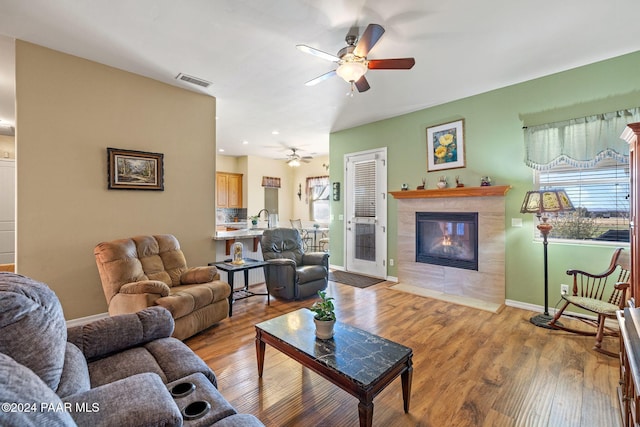 living room featuring a fireplace, wood finished floors, a ceiling fan, and visible vents