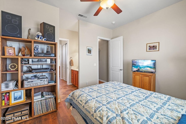 bedroom featuring connected bathroom, visible vents, baseboards, and wood finished floors