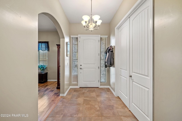 entryway featuring an inviting chandelier, baseboards, and arched walkways