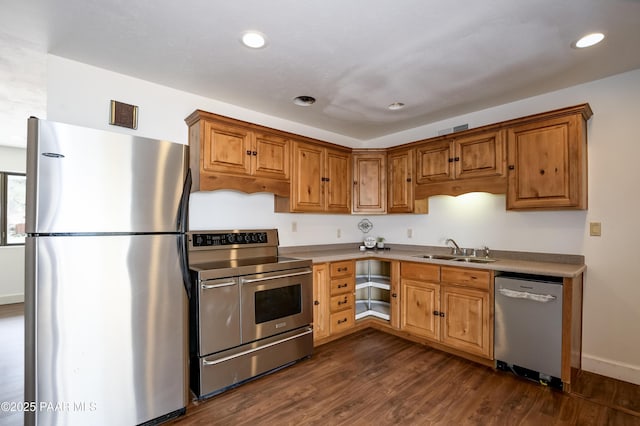 kitchen with appliances with stainless steel finishes, dark wood finished floors, a sink, and recessed lighting