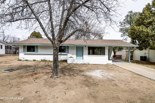 ranch-style home with an attached carport, central AC, driveway, and roof with shingles