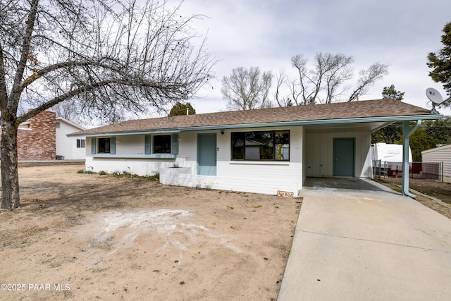 ranch-style house featuring driveway, a carport, and roof with shingles