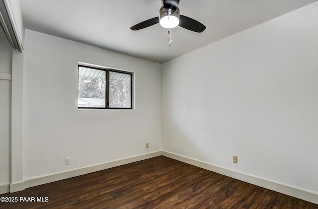 spare room featuring dark wood-style floors, baseboards, and a ceiling fan