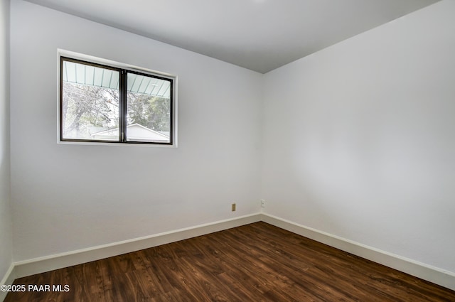 unfurnished room with dark wood-type flooring and baseboards