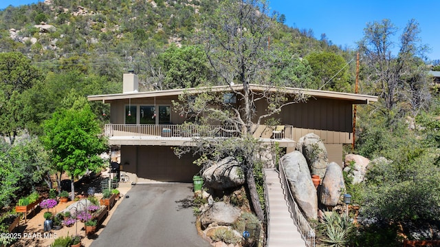 2009 Rocky Dells Dr, Prescott, AZ 86303 - view of front of property with driveway, an attached garage, a chimney, a view of trees, and a balcony