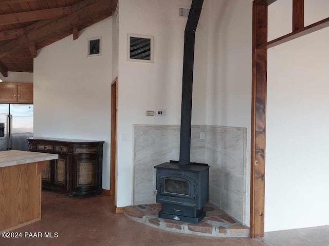 room details with a wood stove, high quality fridge, and concrete flooring