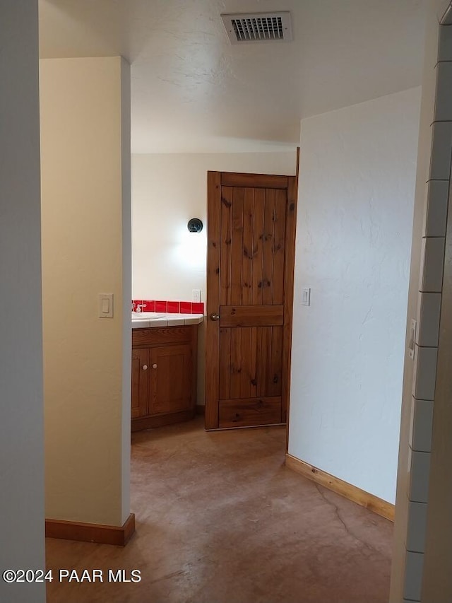 hallway with light colored carpet and sink