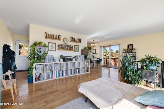 bedroom with access to outside, an inviting chandelier, and light hardwood / wood-style floors