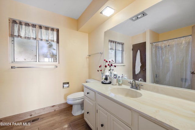 bathroom with hardwood / wood-style floors, vanity, toilet, and curtained shower