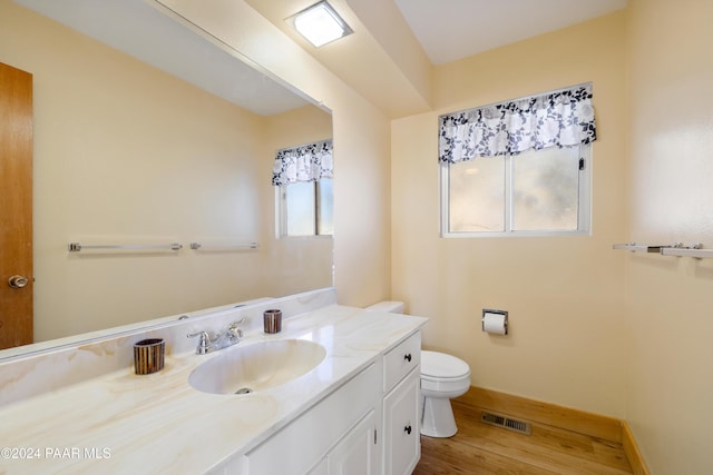 bathroom featuring toilet, plenty of natural light, vanity, and hardwood / wood-style flooring