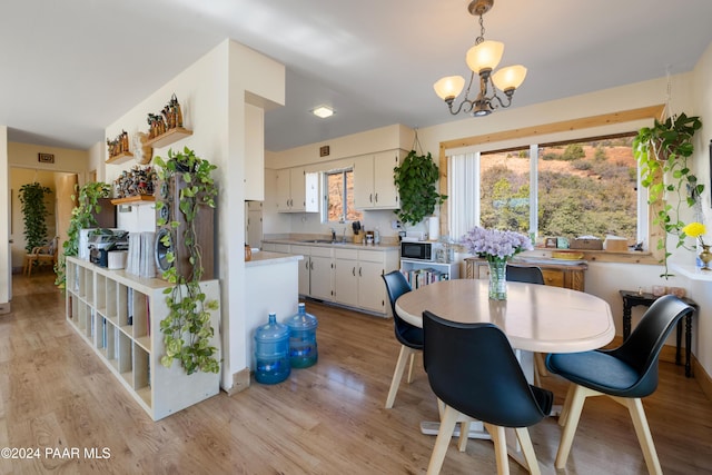 dining space featuring light hardwood / wood-style floors, sink, and an inviting chandelier