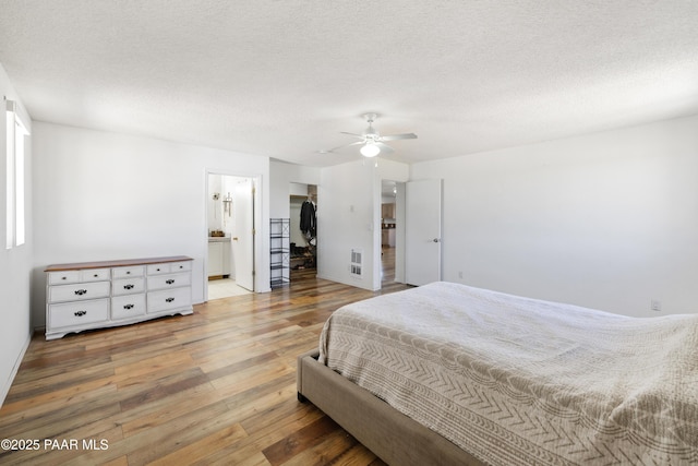 8910 S Steven Trl, Kirkland, AZ 86332 - bedroom featuring light wood finished floors, ceiling fan, a textured ceiling, a spacious closet, and connected bathroom