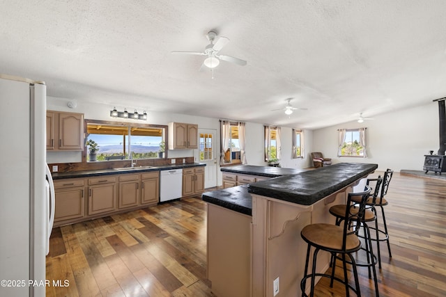 8910 S Steven Trl, Kirkland, AZ 86332 - kitchen featuring white appliances, a sink, a textured ceiling, hardwood / wood-style floors, and a kitchen bar