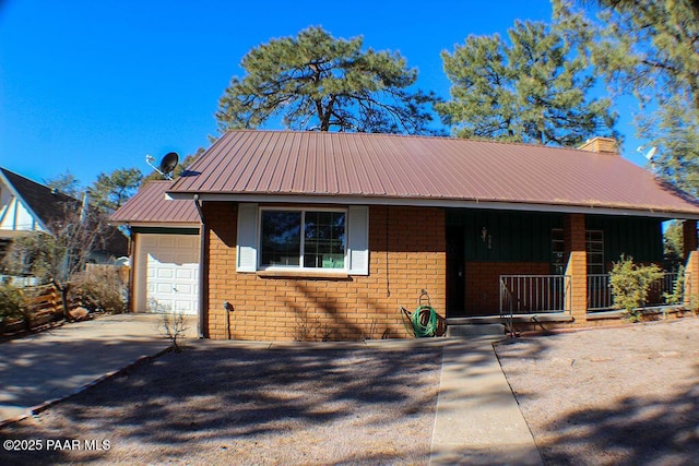 view of front facade featuring driveway, a chimney, brick siding, metal roof, and a garage