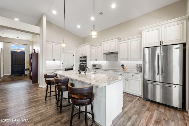 12612 E E Side Saddle Ln, Prescott Valley, AZ 86315 - kitchen featuring appliances with stainless steel finishes, high vaulted ceiling, tasteful backsplash, a center island with sink, and white cabinets